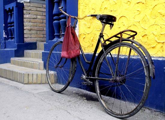 Bicycle leaning against a blue and yellow wall